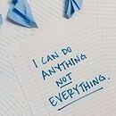 There is an array of crumpled up blue post-its and loose-leaf paper, one of the pages having the following written on it: "I can do anything, not everything."