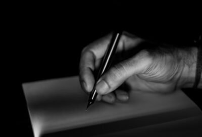 Black and white photo of male hand holding a black pen