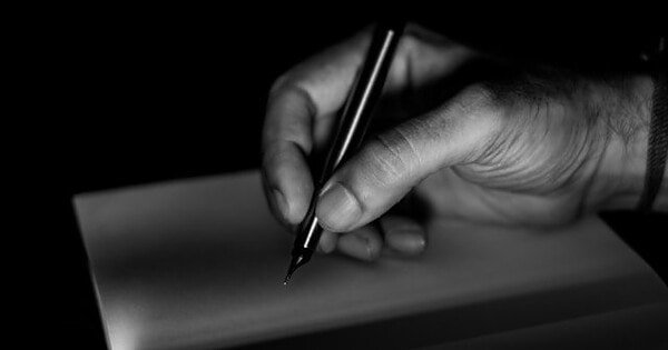 Black and white photo of male hand holding a black pen