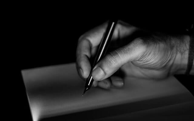 Black and white photo of male hand holding a black pen