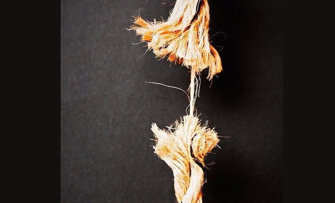 Frayed rope hanging on by a thread