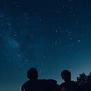 2 people staring at the night sky full of stars