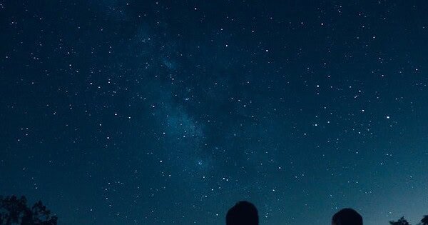 2 people staring at the night sky full of stars