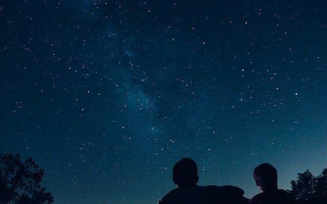 2 people staring at the night sky full of stars