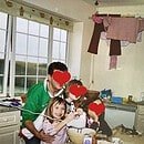 A little girl grinning ecstatically as she whisks up a concoction. Her family are with her and their faces are obscured for privacy.