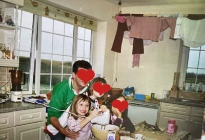A little girl grinning ecstatically as she whisks up a concoction. Her family are with her and their faces are obscured for privacy.