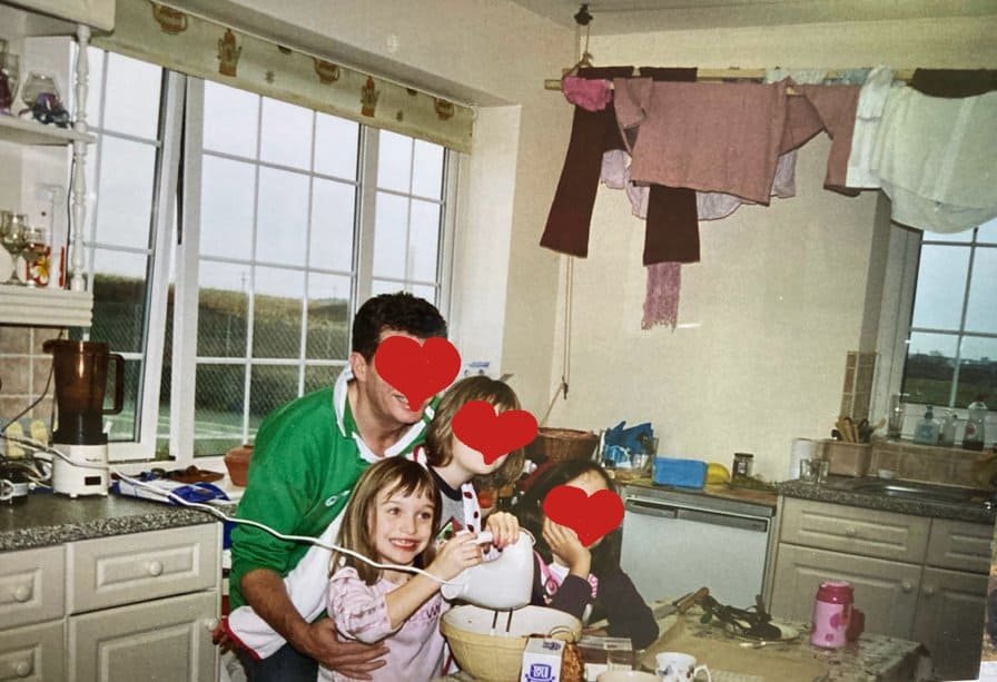 A little girl grinning ecstatically as she whisks up a concoction. Her family are with her and their faces are obscured for privacy.