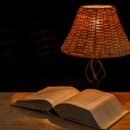A lamp beside an open book on a wooden desk
