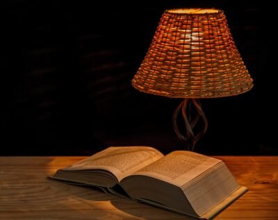 A lamp beside an open book on a wooden desk