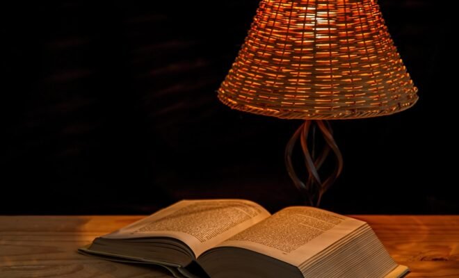 A lamp beside an open book on a wooden desk