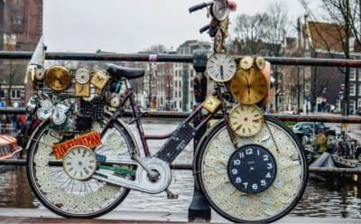 The image is of a weird 'clock' bike on a bridge over river.