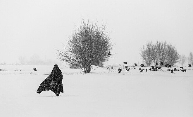 A person walking in the snow with a long coat on