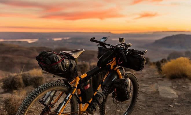 Bike on a hill with a view of a yellow and orange sunset