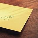 A yellow sticky note with an apology on a brown table