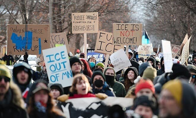Protesters in Minneapolis gather on the spot where Renee Good was killed, holding signs that read, "When these colonies gonna rise up?", "ICE out of MN", "Renee sparkled! Fight for our neighbors". "Fuck ICE", and "ICE is not welcome (with not emphasized in red)".