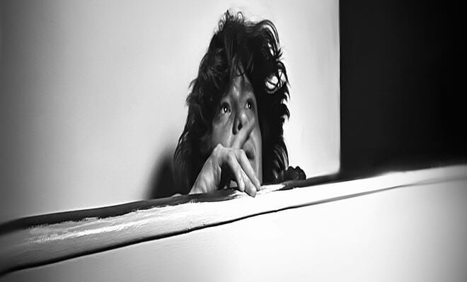 A woman staring off with a black and white background.