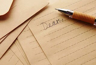 Lined paper with the word "dear" written in cursive and a fountain pen next to it