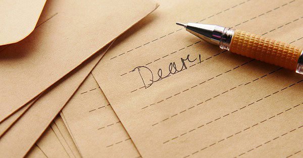 Lined paper with the word "dear" written in cursive and a fountain pen next to it