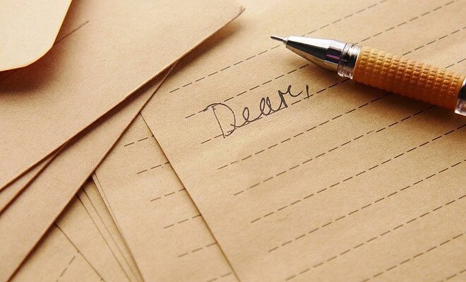 Lined paper with the word "dear" written in cursive and a fountain pen next to it