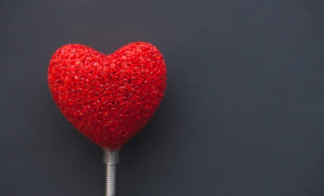 A red heart on a white stem against a dark gray background