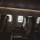 Three rows of seats line portal windows along the dimly lit interior of a commercial aircraft