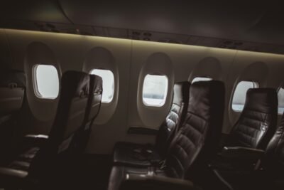 Three rows of seats line portal windows along the dimly lit interior of a commercial aircraft