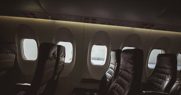 Three rows of seats line portal windows along the dimly lit interior of a commercial aircraft