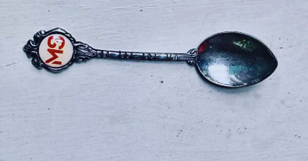 The image is of silver teaspoon with the initials "MS" (Multiple Sclerosis) embossed on the handle button.
