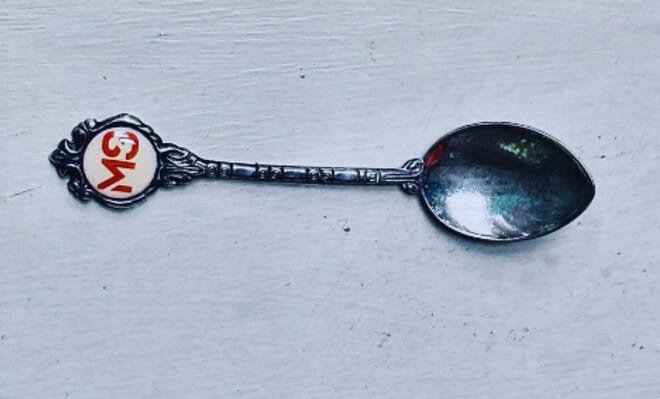 The image is of silver teaspoon with the initials "MS" (Multiple Sclerosis) embossed on the handle button.