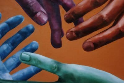 Four multi-colored hands reaching for each other against an orange background