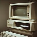 A gray square shaped computer device with a blank brown background.