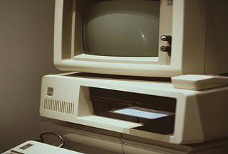A gray square shaped computer device with a blank brown background.