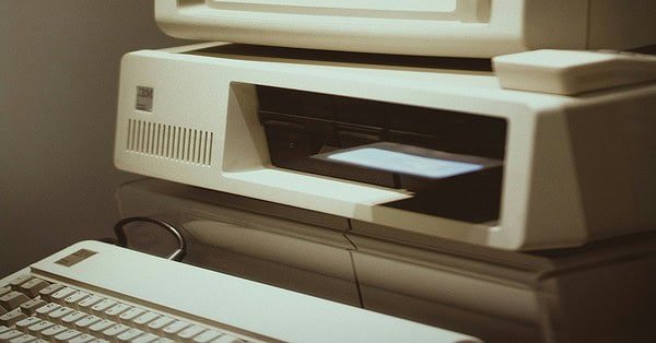 A gray square shaped computer device with a blank brown background.