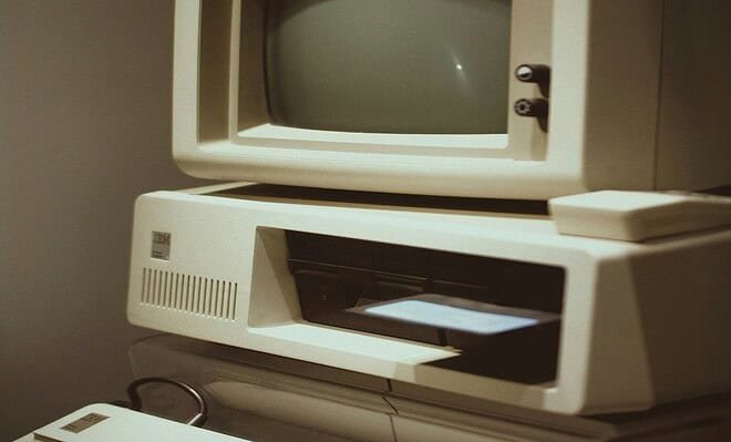 A gray square shaped computer device with a blank brown background.