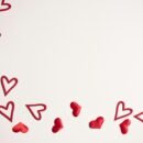 There is a white background with a flurry of hearts filling the left side of the picture, flowing along the bottom towards the bottom right corner of the photo