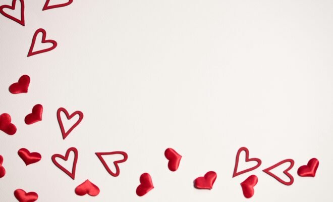 There is a white background with a flurry of hearts filling the left side of the picture, flowing along the bottom towards the bottom right corner of the photo