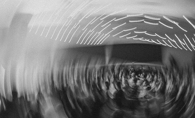 A party in gray scale spins in a circle, drawing the lights in a spiral.