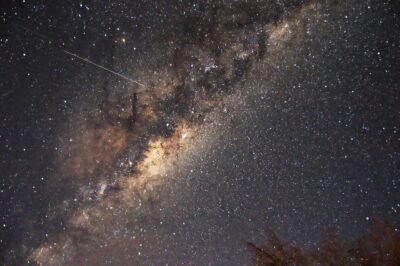 A shooting star streaks across the bright stars outlining the disk of the Milky Way