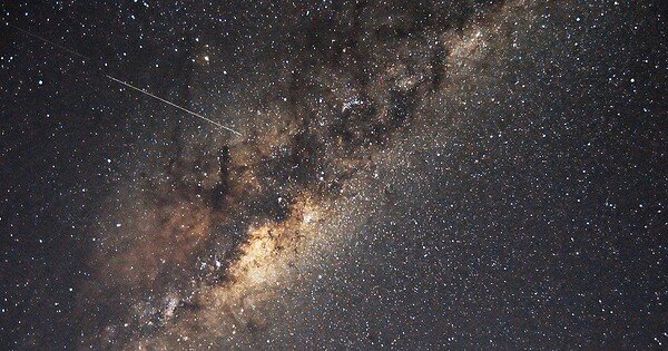 A shooting star streaks across the bright stars outlining the disk of the Milky Way