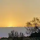 The image is of a fawn twilight sky sitting over the setting sun and a grey cloud band, which could be interpreted as a 'Timeline.'