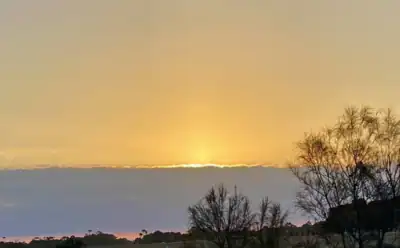 The image is of a fawn twilight sky sitting over the setting sun and a grey cloud band, which could be interpreted as a 'Timeline.'