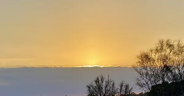 The image is of a fawn twilight sky sitting over the setting sun and a grey cloud band, which could be interpreted as a 'Timeline.'
