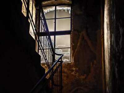 A dark and barely lit staircase with a window facing the fading sun