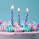 There is a blue background and the top of a pink cake could be seen, covered in blue and pink frosting with three candles on top.