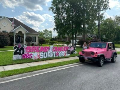 Yard sign says 20 year breast cancer survivor and a pink jeep at the curb