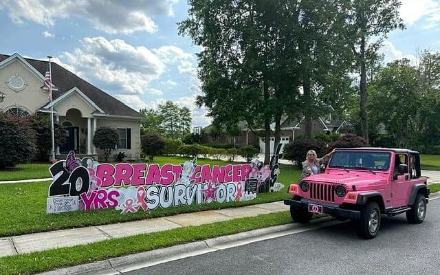 Yard sign says 20 year breast cancer survivor and a pink jeep at the curb