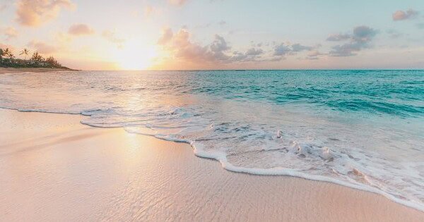 View of a calm beach with the sun at the horizon
