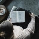 A lady sitting with her legs crossed reading a book