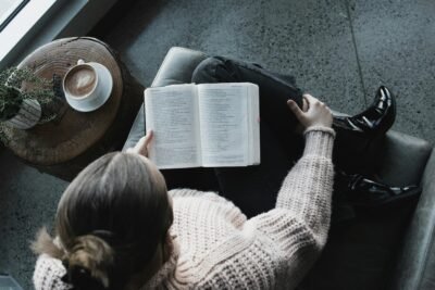 A lady sitting with her legs crossed reading a book