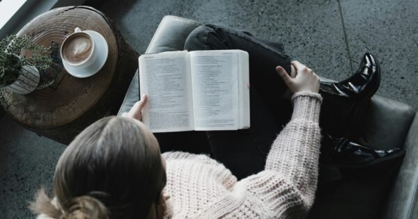 A lady sitting with her legs crossed reading a book